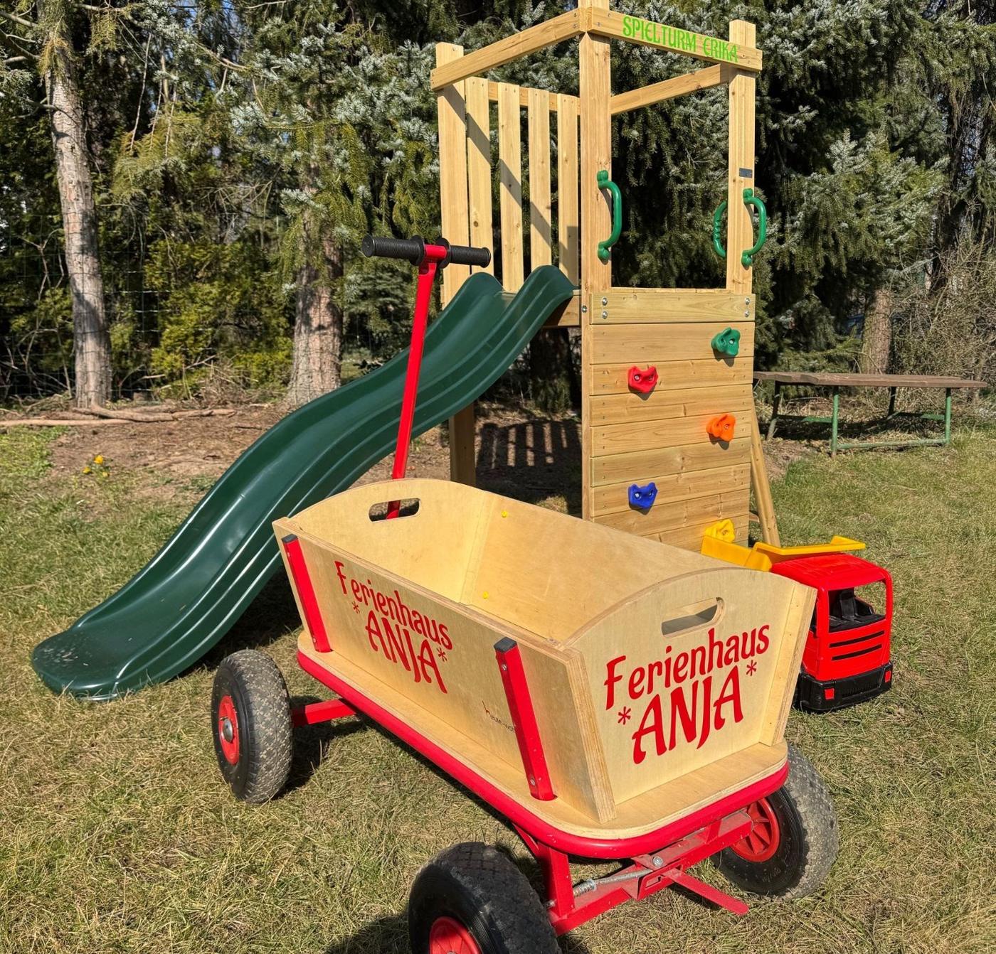 Bollerwagen mit Aufschrift Ferienhaus Anja vor dem Spielturm